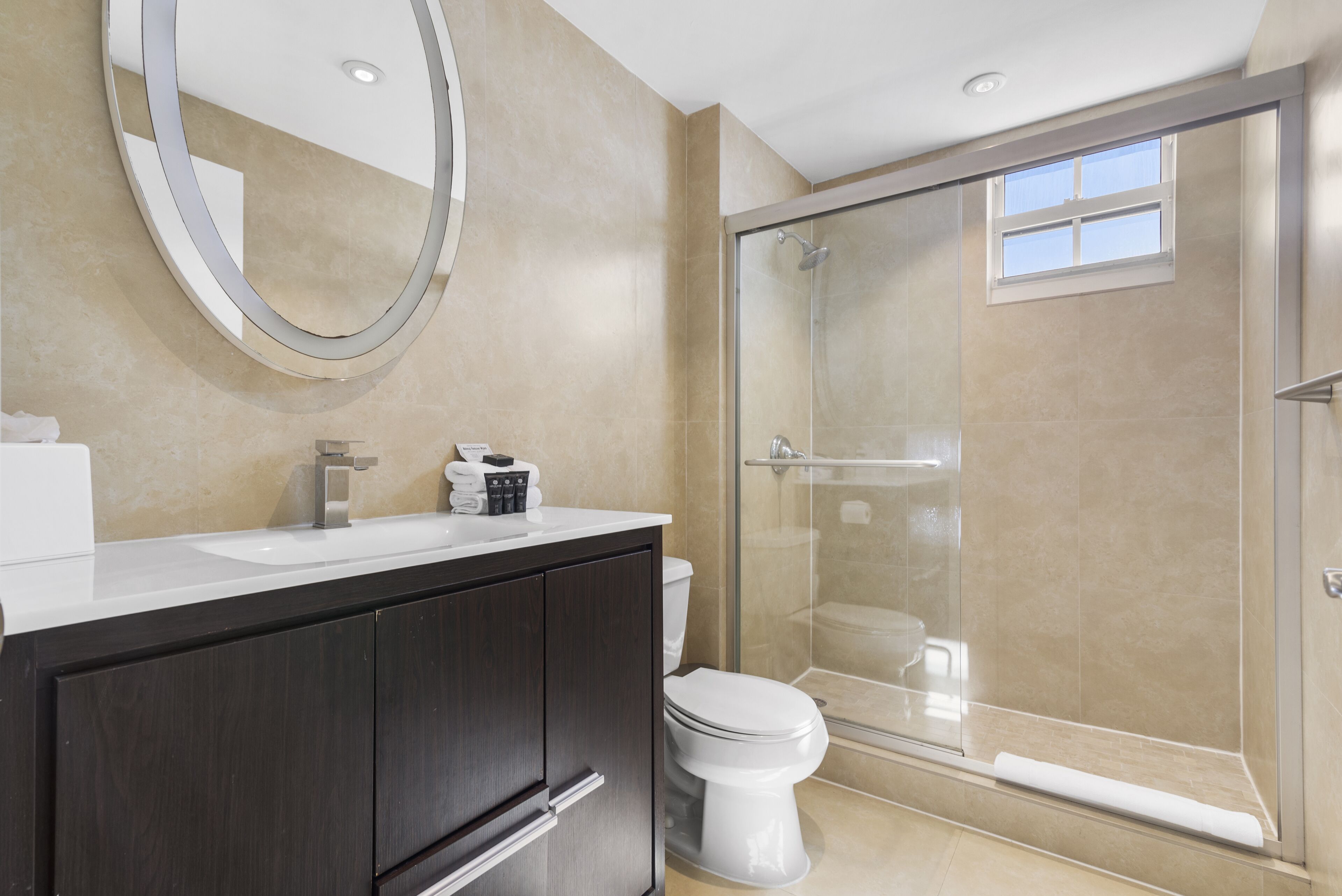 Une salle de bain moderne avec une douche à parois de verre, un lavabo blanc et des meubles en bois foncé.