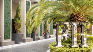 A modern building with a paved walkway, green vertical gardens, and a palm tree. - Fortune House Hotel Suites (Miami)