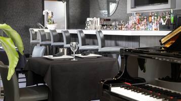 Un área de comedor con un piano, una barra con varias botellas y un espejo grande en la pared.