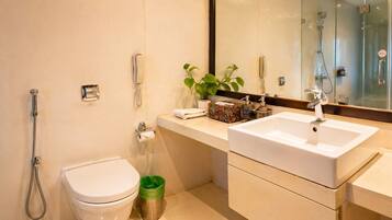 A modern bathroom with a toilet, bidet, shower, and a sink with a mirror above it.