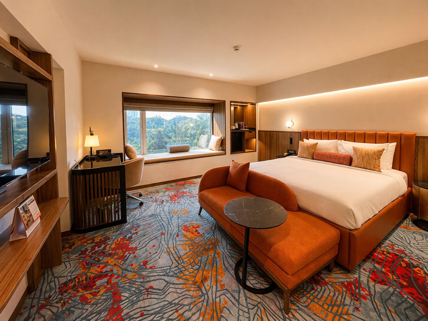 Habitación de hotel con una cama grande, un sofá, un escritorio con lámpara, ventana con vistas y una mesita.
