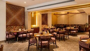 A restaurant with multiple tables and chairs, a patterned carpet, and a decorative wall with a lattice design.