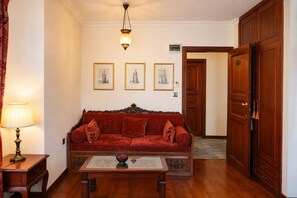 Une pièce avec un canapé rouge, une table basse en bois, une lampe et des tableaux encadrés accrochés au mur.