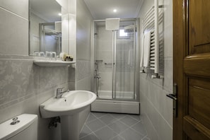 Un baño moderno con inodoro, lavabo y cabina de ducha de vidrio.