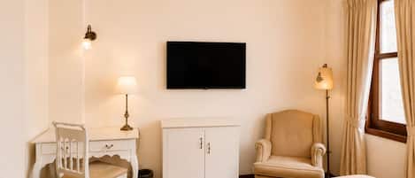Una habitación de hotel con una cama, un escritorio, una silla, un televisor y una lámpara.