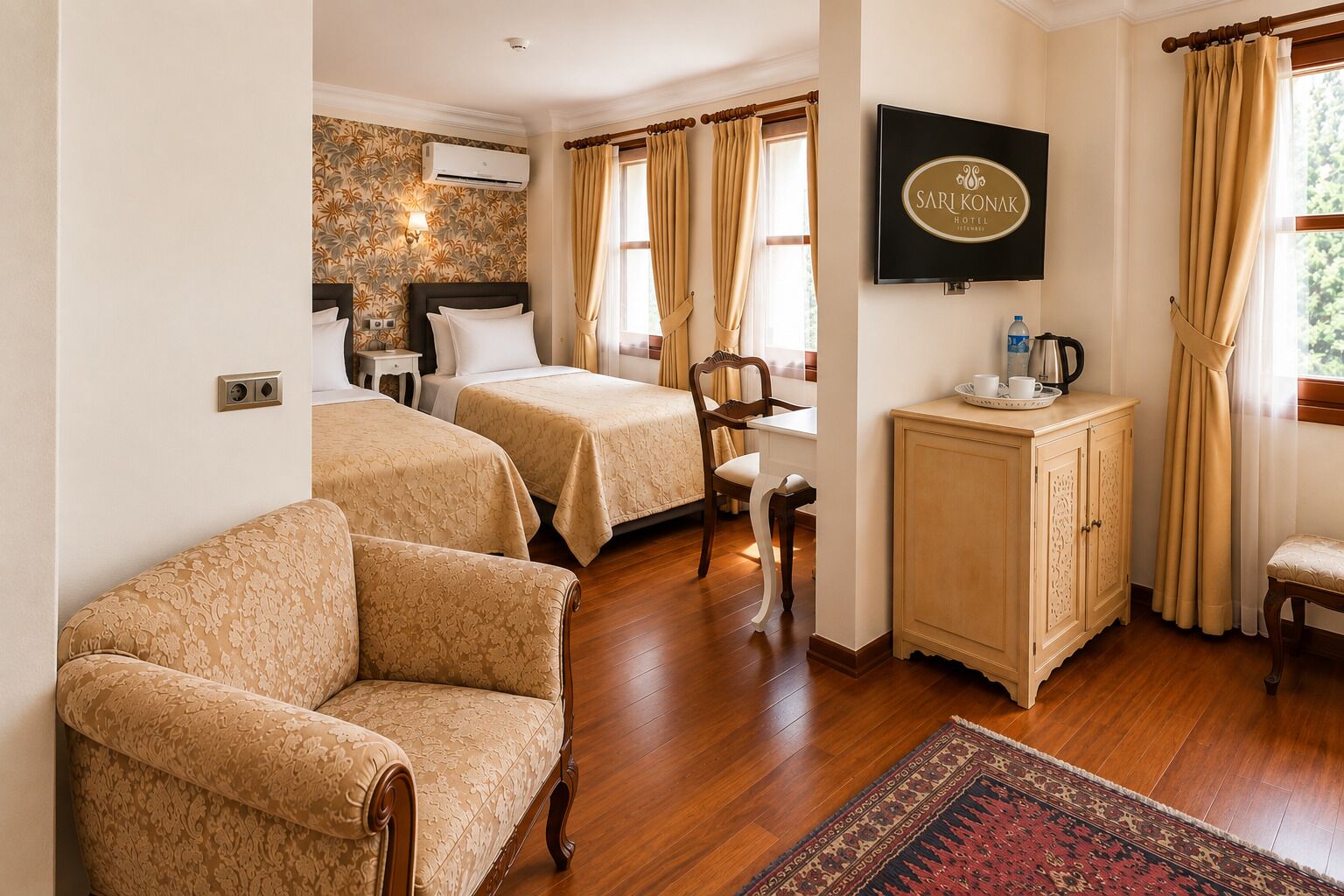 A hotel room with two beds, a TV, a desk with a chair, a cabinet, and a patterned rug.