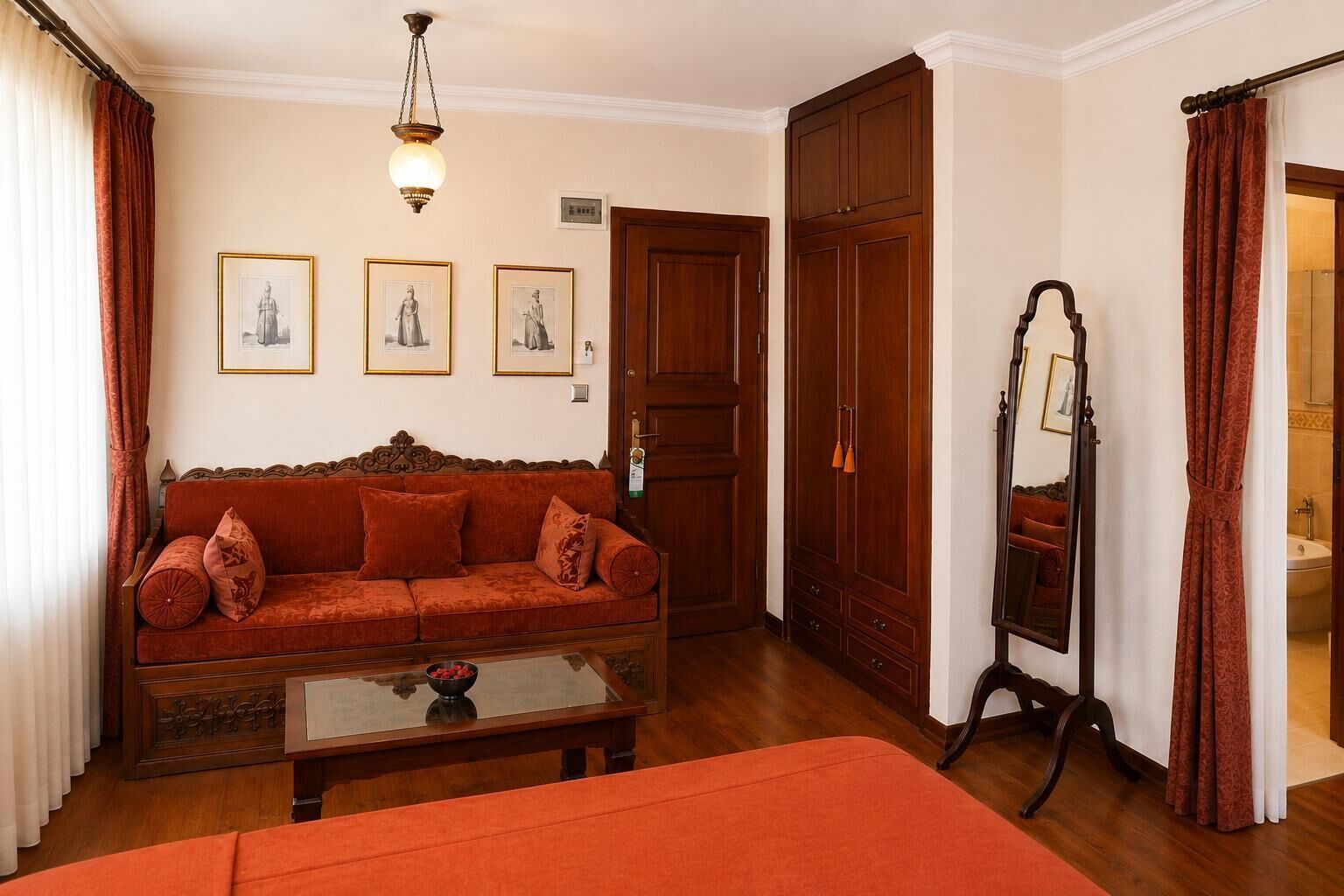 Um quarto com sofá, mesa com tigela, espelho e guarda-roupa.