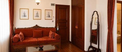 Um quarto com sofá, mesa com tigela, espelho e guarda-roupa.
