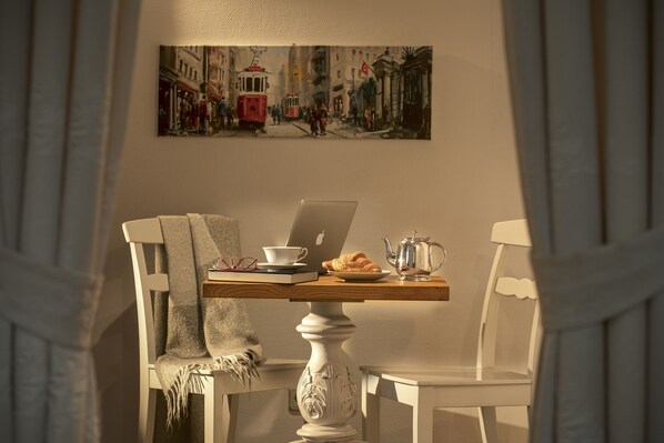 Une table à manger avec un ordinateur portable, une tasse, une assiette de nourriture et une théière.