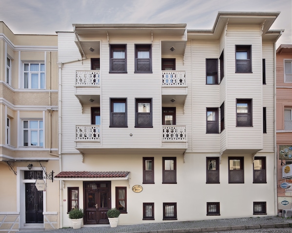Un edificio de varios pisos con balcones, un letrero que indica un restaurante y una calle adoquinada.