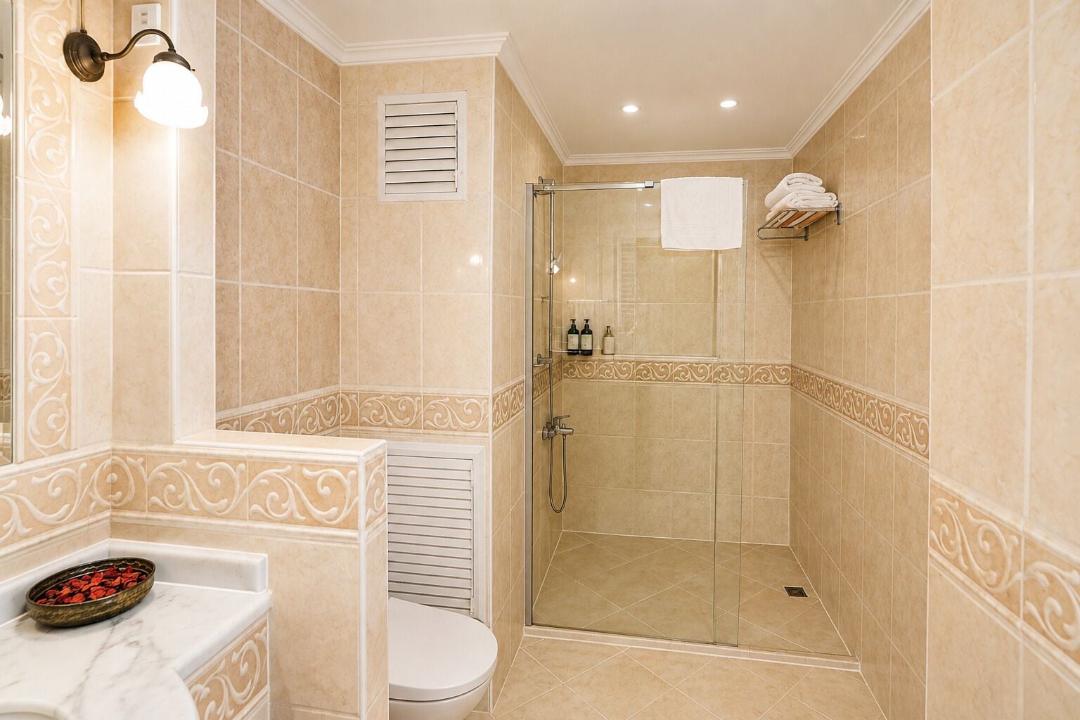 Une salle de bain dotée d’une douche à parois de verre, de toilettes et d’un lavabo agrémenté d’un récipient décoratif.