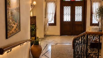 Un escalier avec une rampe, une porte avec des panneaux de verre et un lustre.
