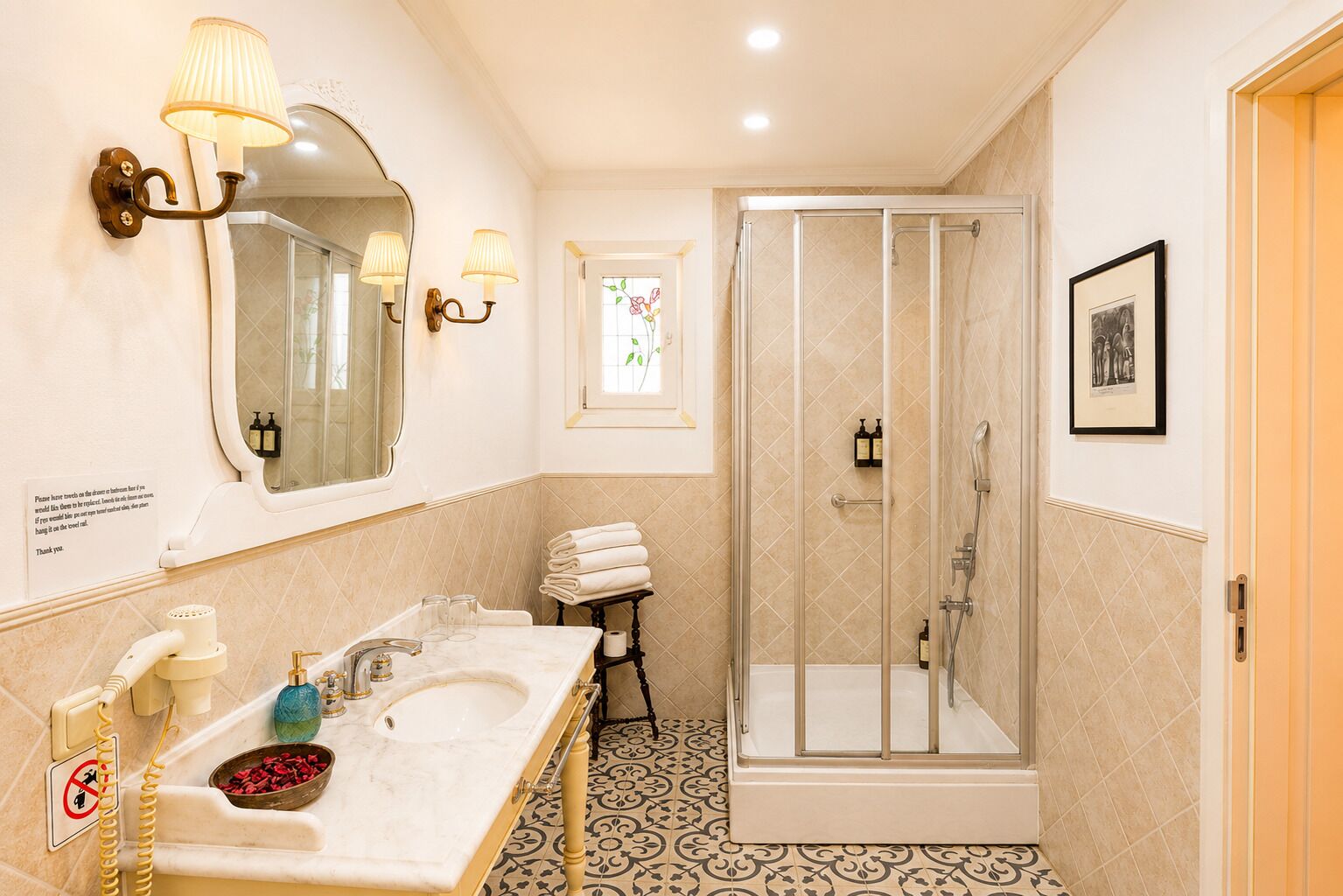 A bathroom with a double sink, a mirror, a shower enclosure, and a framed picture on the wall.
