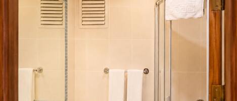Un baño con lavamanos, espejo, toallero, ducha y lámpara.