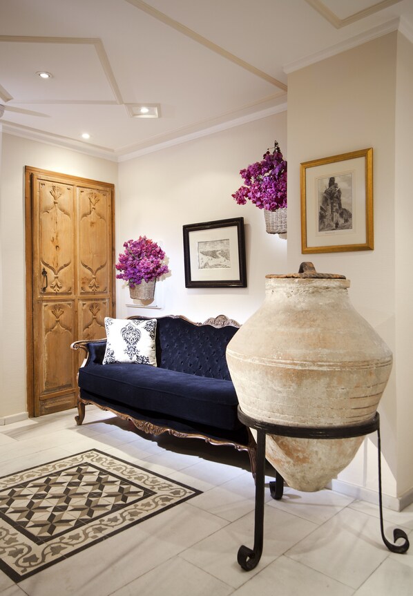 A room with a dark blue sofa, a large white vase, and a wooden door.