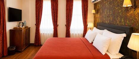 Habitación de hotel con una cama grande, televisor de pantalla plana, mueble de madera, dispensador de agua y aire acondicionado instalado en la pared.