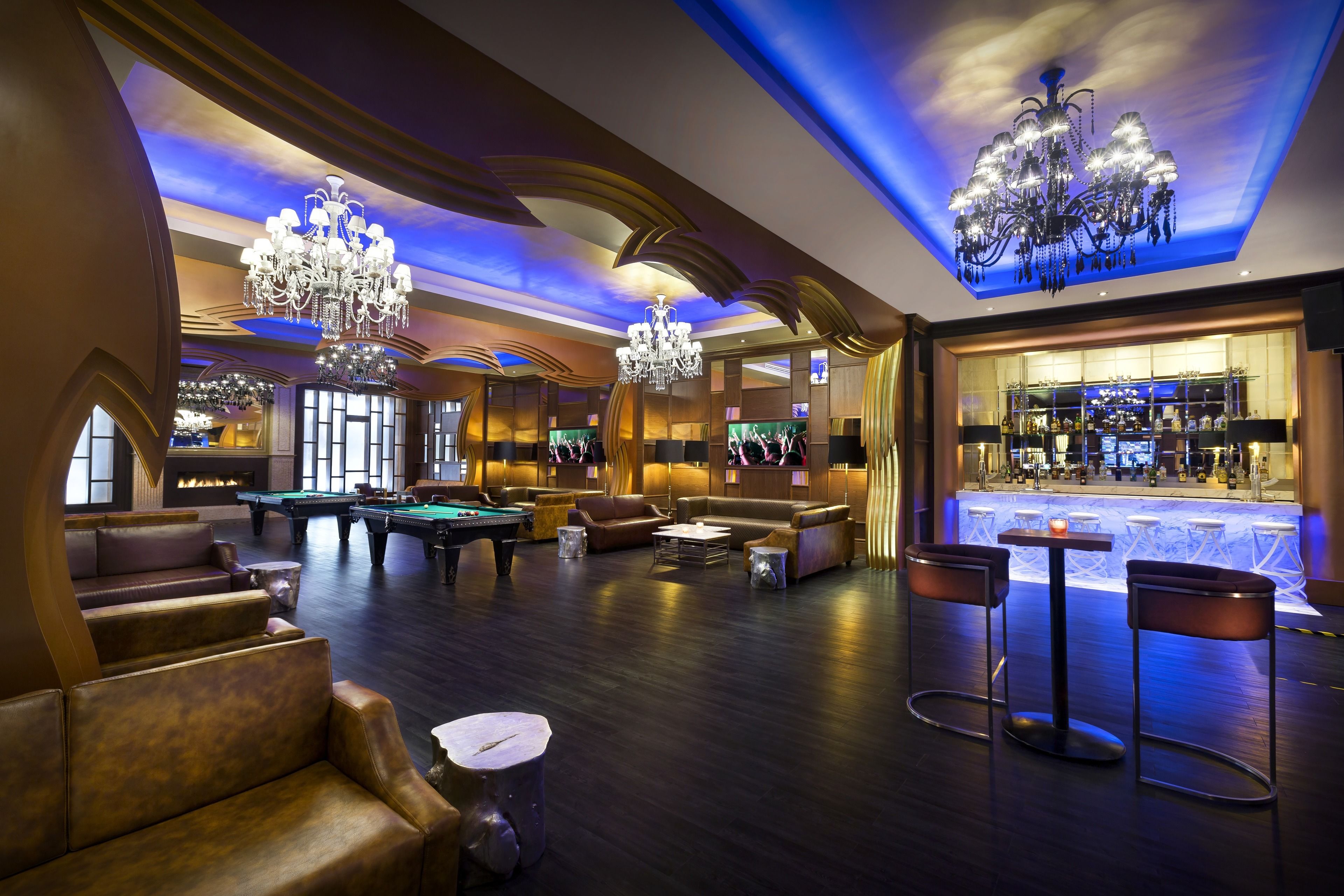 Un amplio salón con asientos de cuero, mesa de billar y bar con interior bien iluminado.