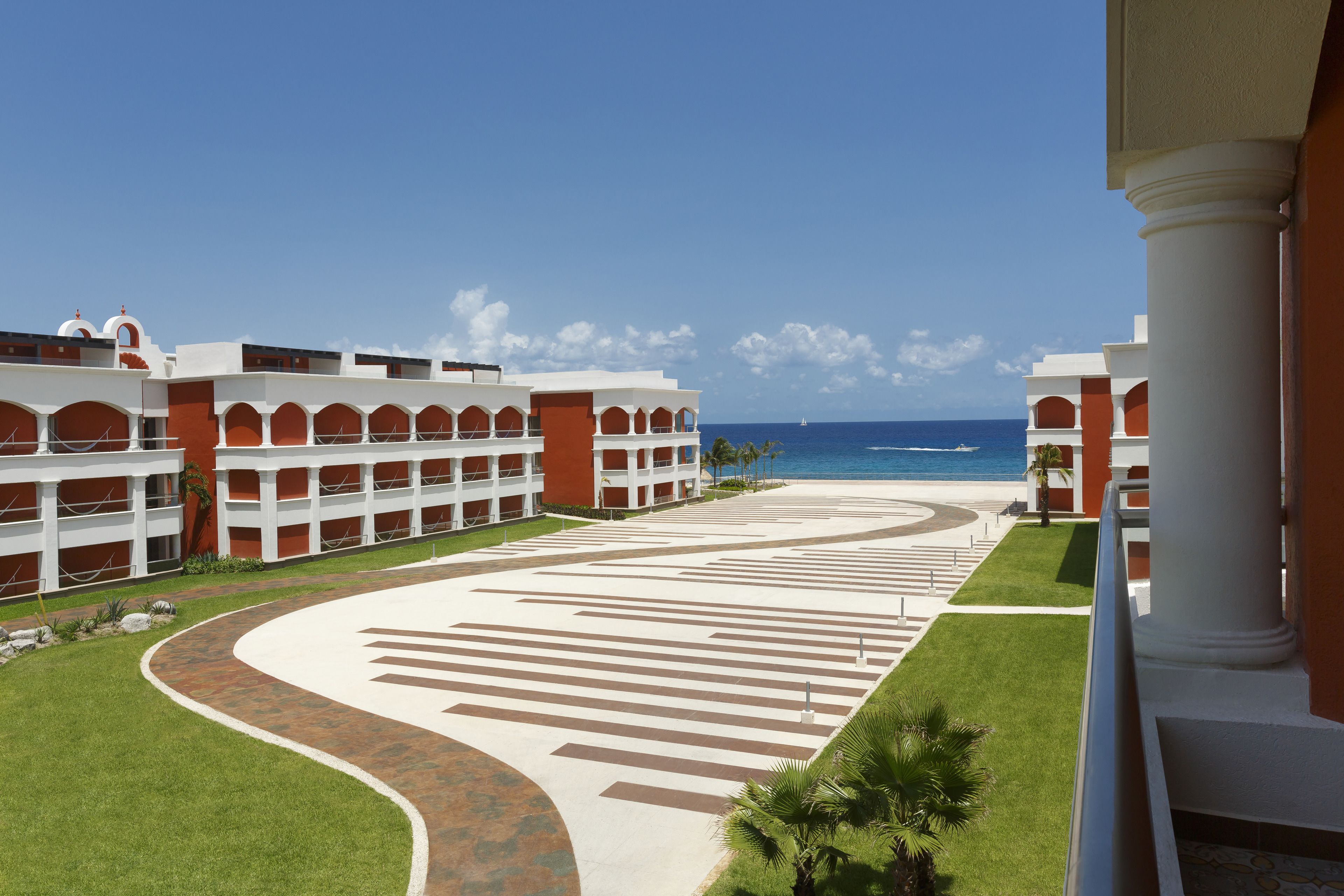 A resort with a central courtyard, multiple buildings, and a view of the ocean.
