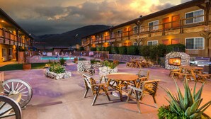 A hotel courtyard with outdoor seating, a pool, and a stone fireplace. - Days Inn by Wyndham Lebec (Lebec)