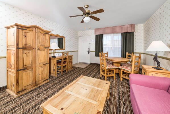 Une pièce comprenant une armoire en bois, une table à manger avec des chaises, un canapé rose et un ventilateur de plafond.