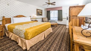 A hotel room with a large bed, a wooden desk, a chair, a ceiling fan, and a window with curtains. - Days Inn by Wyndham Lebec (Lebec)
