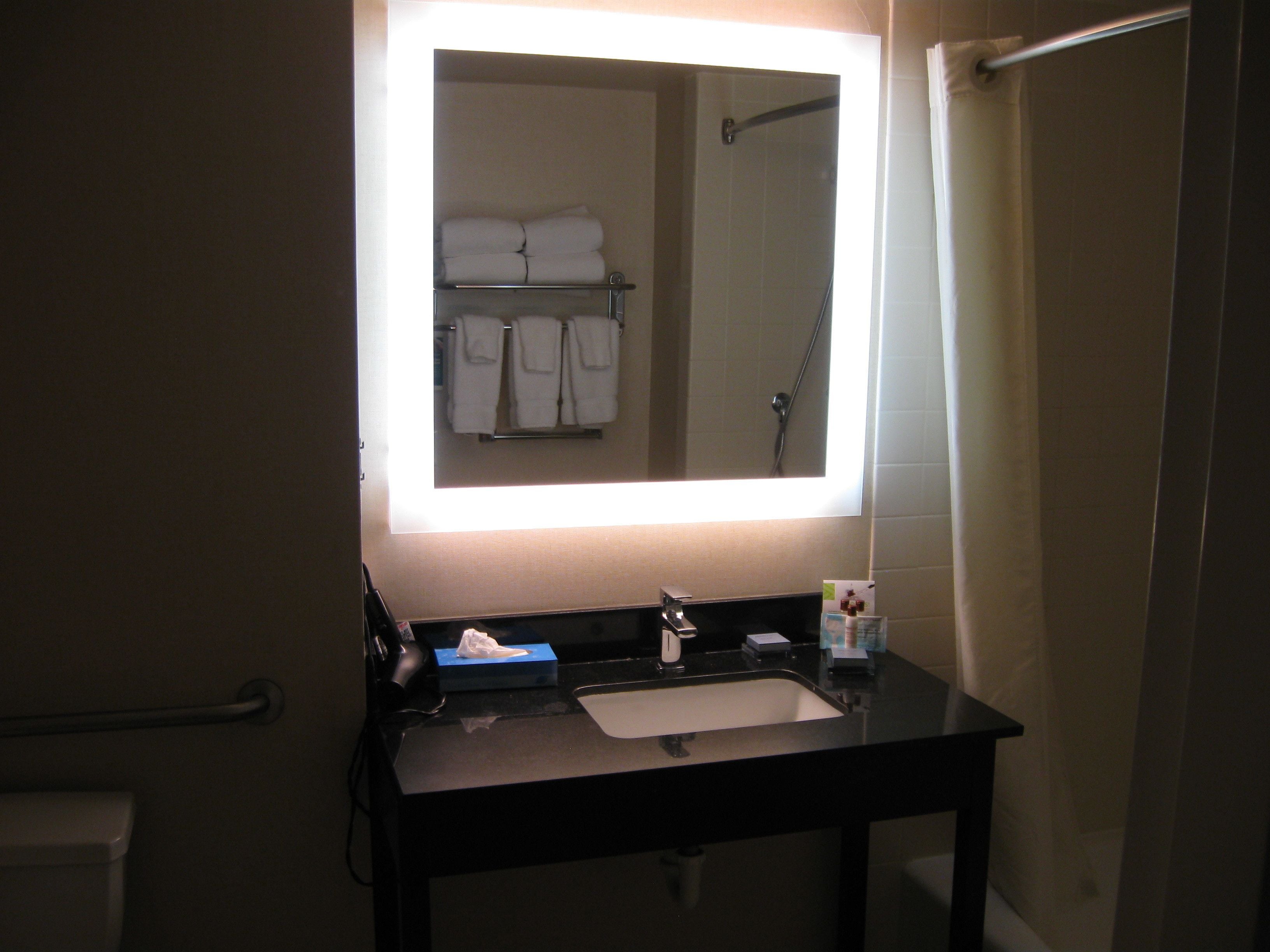 A bathroom with a black sink, a mirror, and a towel rack with folded towels.