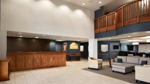Eine geräumige Lobby mit Empfangsschalter, Sitzgelegenheiten und einer Treppe.