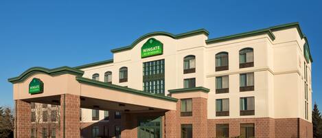 A Wingate hotel with a brick facade, green awning, and multiple windows.