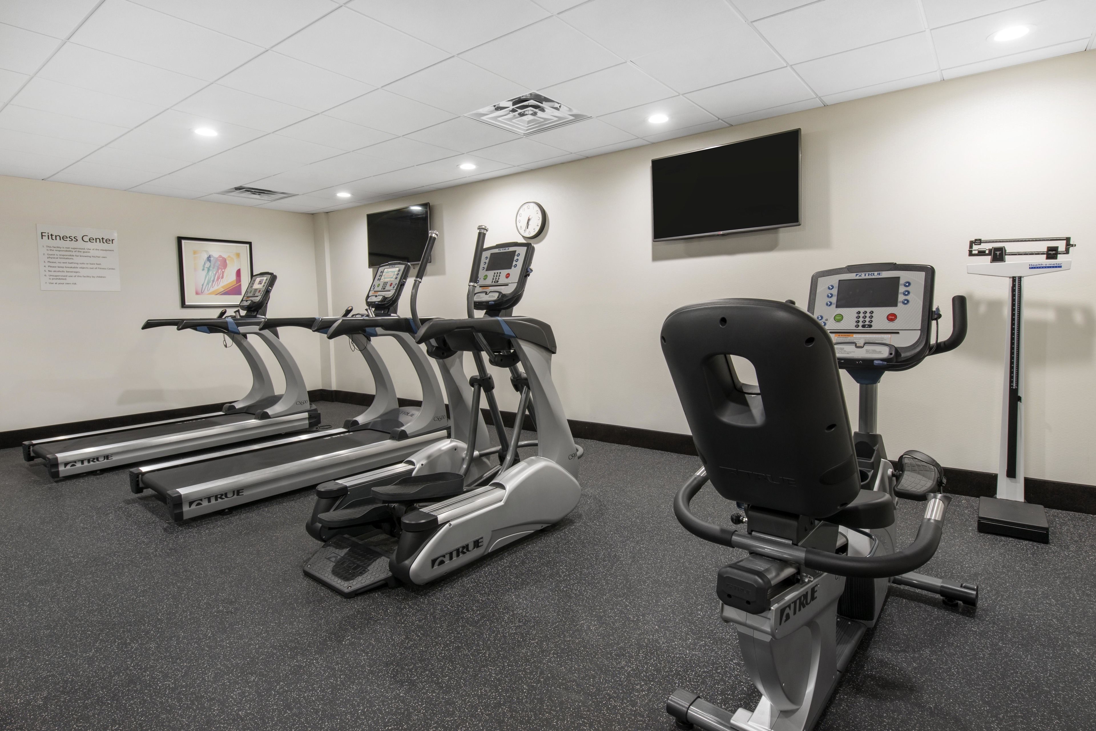 Un gimnasio con cintas de correr, elíptica y bicicleta estática.