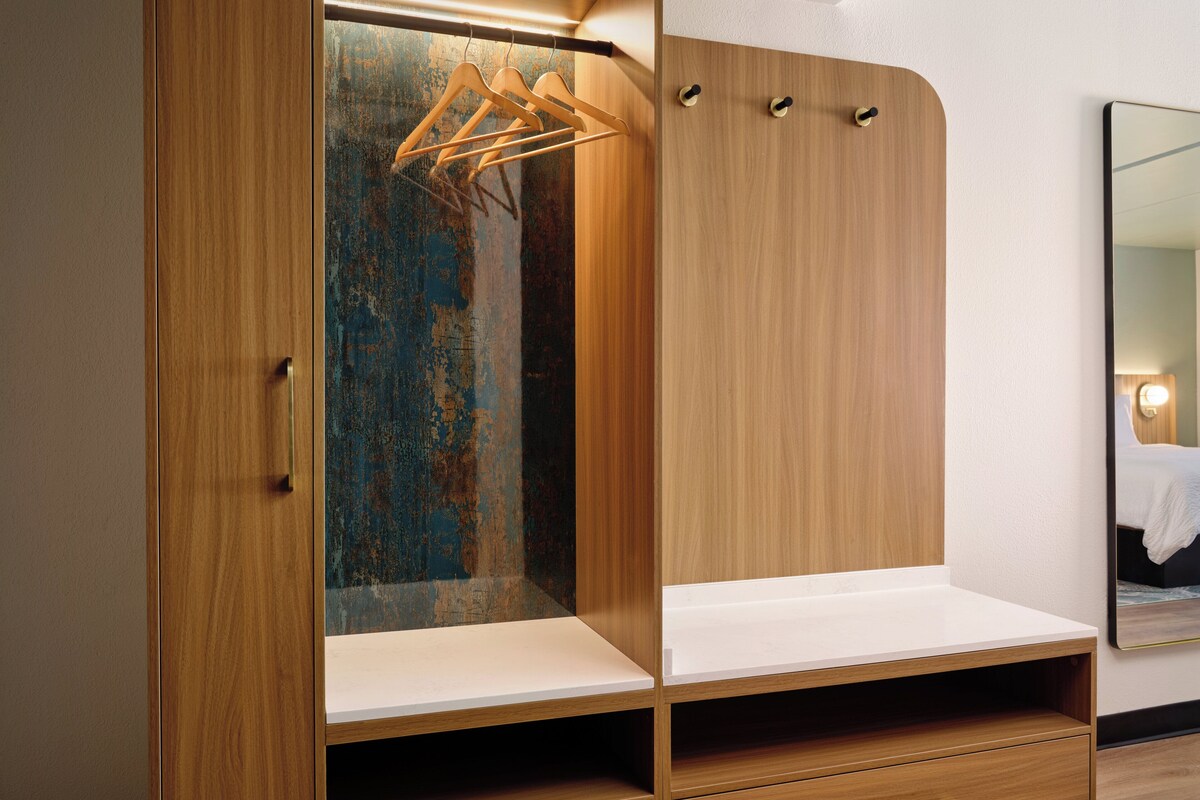 A wooden wardrobe with a mirror and a bench.