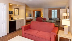 A hotel room with a kitchenette, a sofa, a dining table, and a separate bedroom area. - La Quinta Inn & Suites by Wyndham Garden City (Garden City)