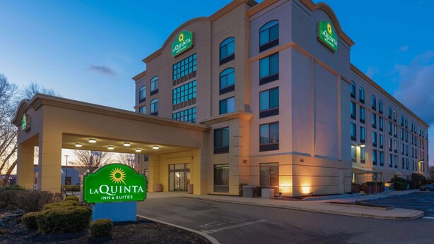 A La Quinta Inn & Suites building with a large entrance, multiple windows, and a well-lit facade. - La Quinta Inn & Suites by Wyndham Garden City (Garden City)