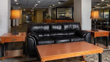 A lobby with a leather sofa, wooden coffee table, and two side tables with lamps.