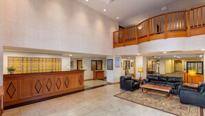 A spacious lobby with a reception desk, seating area, and a balcony. - La Quinta Inn & Suites by Wyndham Garden City (Garden City)