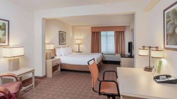 Habitación de hotel con cama, escritorio, sillas, lámparas y televisor.