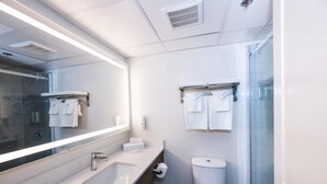 Een moderne badkamer met een grote spiegel, een wastafel, toilet en douchegedeelte.