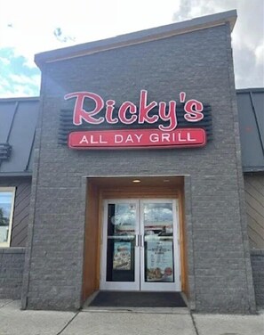 Un bâtiment sur lequel est apposée une enseigne indiquant : « Ricky’s, grill ouvert toute la journée ».