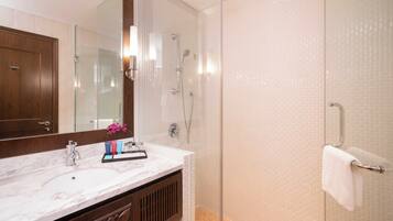 A bathroom with a marble sink, a glass-enclosed shower, and a towel rack.