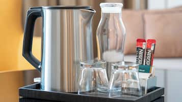 Un plateau contenant une cafetière en acier inoxydable, deux bouteilles en verre et un support pour capsules Nespresso.