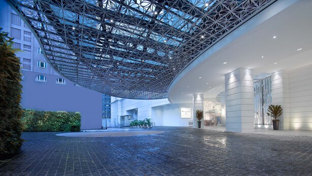A modern hotel lobby with a geometric ceiling design, a brick floor, and a reception area with a plant. - Rendezvous Hotel Singapore by Far East Hospitality (Singapore)