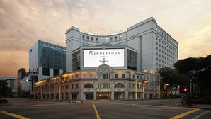 The exterior of the Rendezvous Hotel in Singapore, featuring a prominent sign, classical architecture, and a modern glass building adjacent to it. - Rendezvous Hotel Singapore by Far East Hospitality (Singapore)