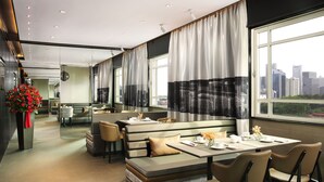 A modern restaurant with high tables and benches, large windows with curtains, and a city view. - Rendezvous Hotel Singapore by Far East Hospitality (Singapore)