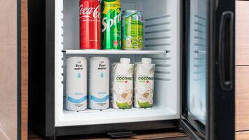 Un refrigerador con bebidas como Coca-Cola, Sprite y té verde jazmín.