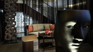 A modern living room with a sofa, a large decorative vase, and a unique sculptural piece. - Rendezvous Hotel Singapore by Far East Hospitality (Singapore)
