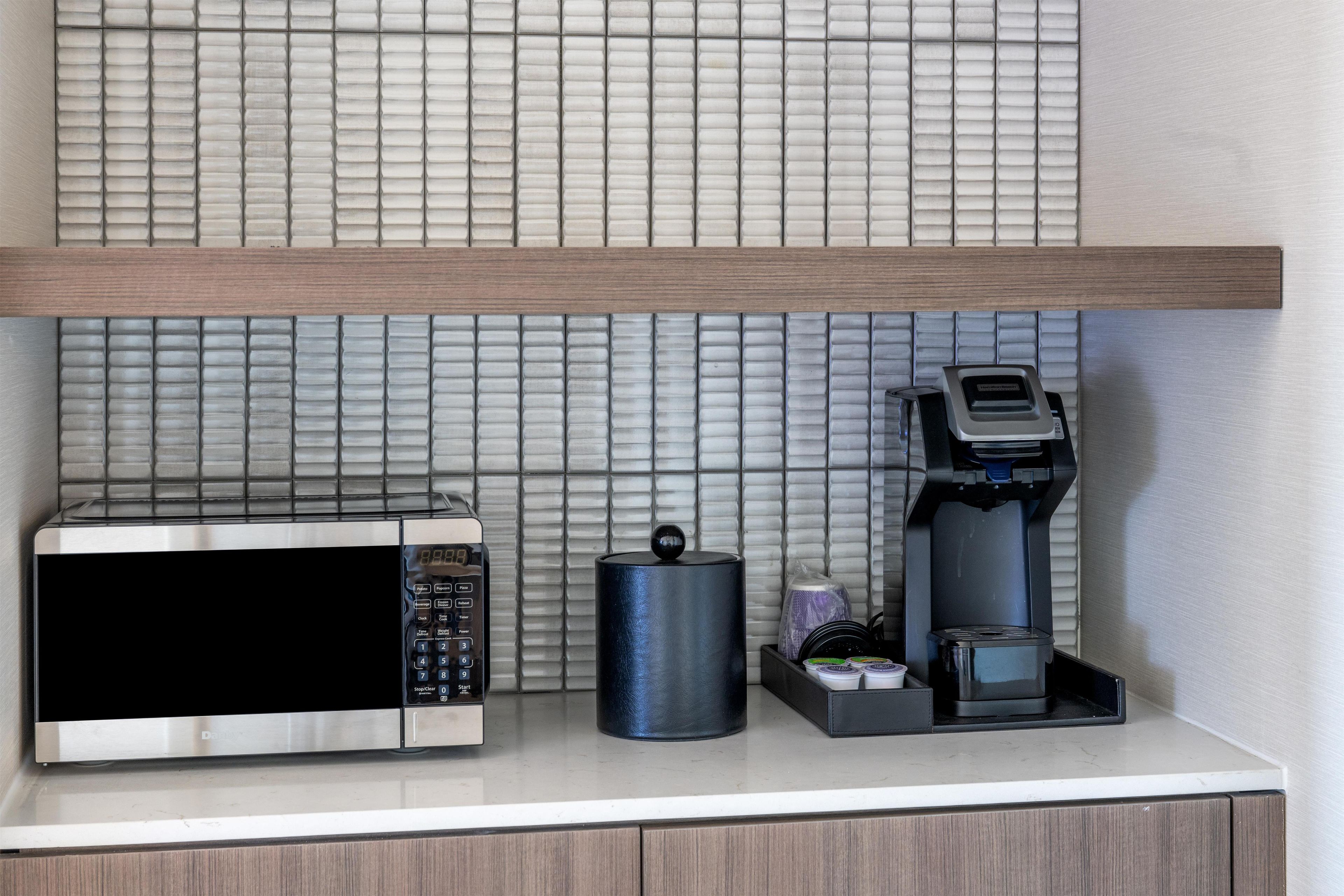 A kitchen counter with a microwave, a coffee maker, and a container.