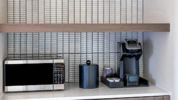 Uma bancada de cozinha com micro-ondas, cafeteira e um recipiente.