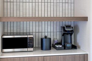 Uma bancada de cozinha com micro-ondas, cafeteira e um recipiente.