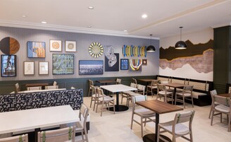 Interior de restaurante con varias mesas y cabinas, obras de arte enmarcadas en las paredes y un mural grande en la pared de fondo.