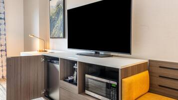 A modern kitchen with a built-in microwave, a flat-screen TV, and a wooden cabinet.