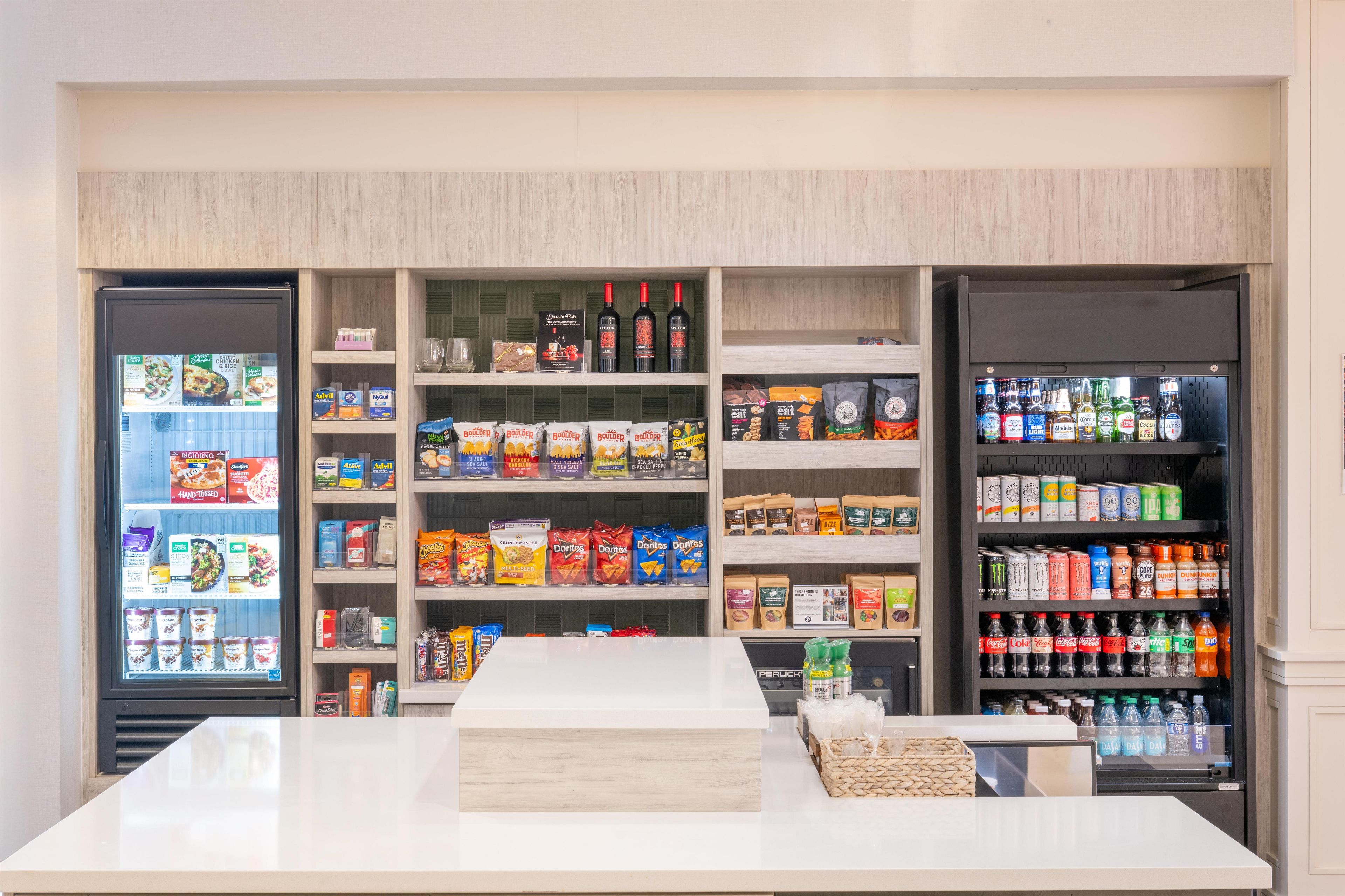A self-service kiosk with refrigerated sections on either side, stocked with snacks, beverages, and packaged goods.